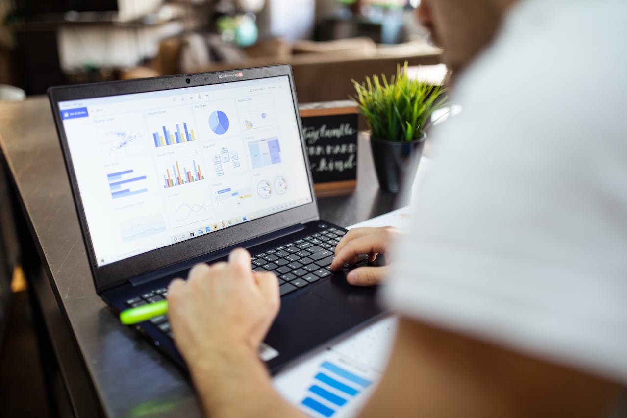 Person working on laptop with graphs displayed.