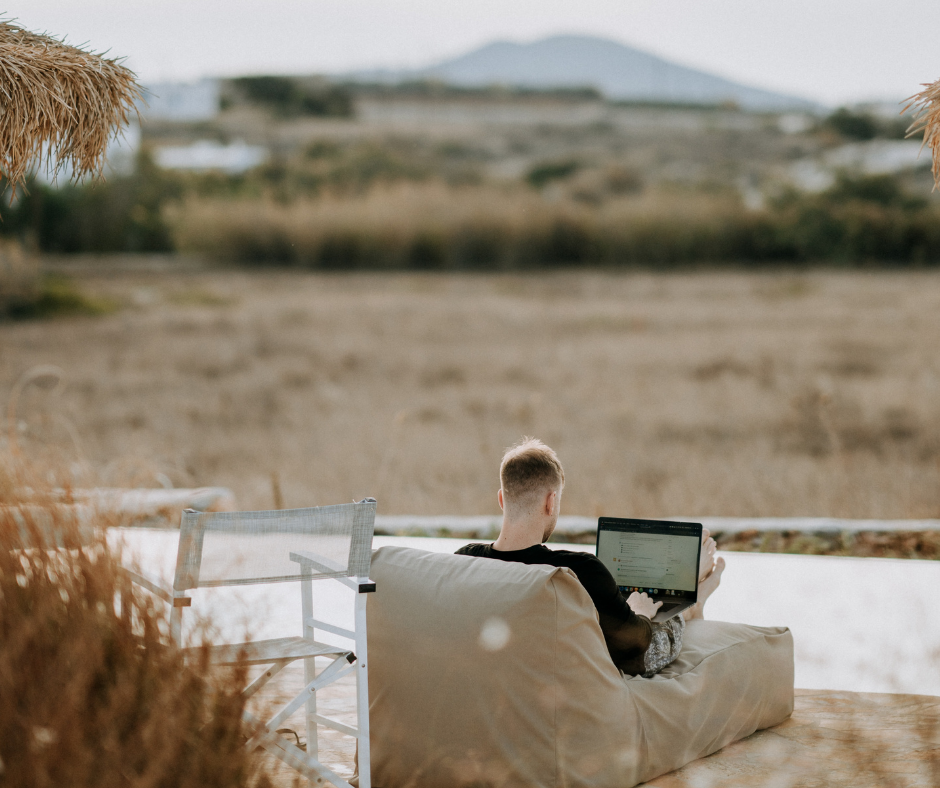 A man sitting on a bean bag chair working on a laptop, relaxed and comfortable, enjoying a moment of leisure and relaxation.