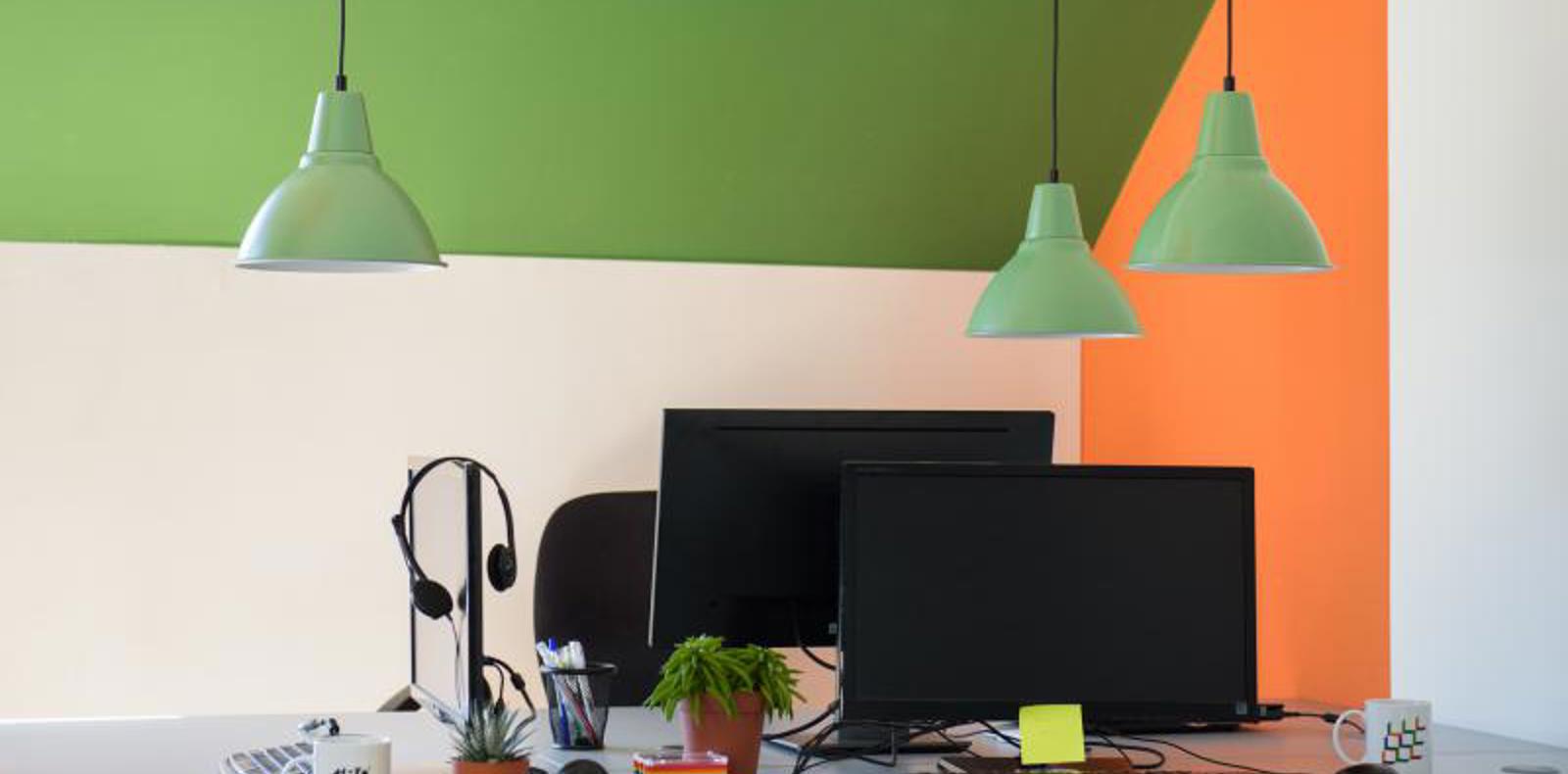 An office setting with a desk, computer, and three lamps.