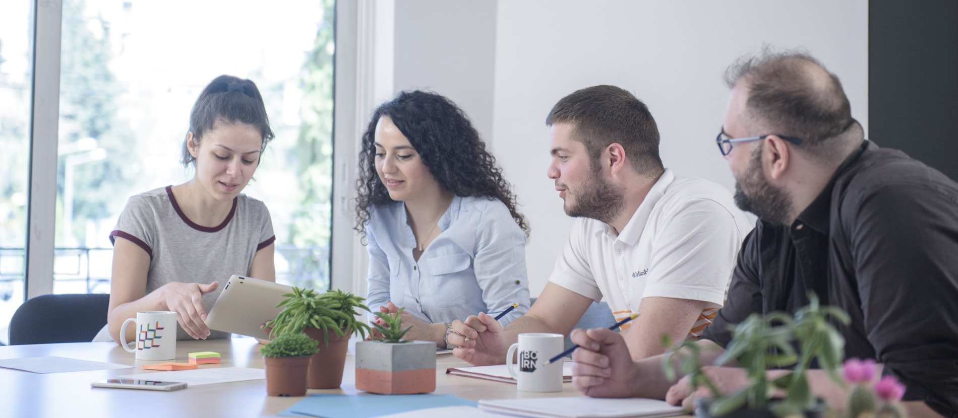 Three people collaborating at a table, focused on a laptop.