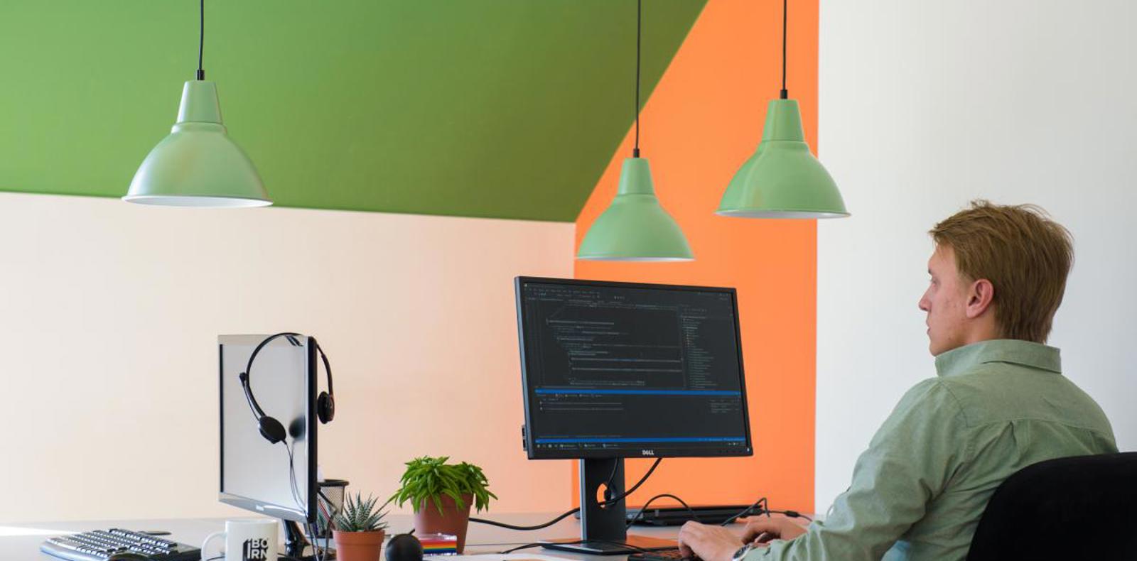 A man working at a desk with a computer and monitor.