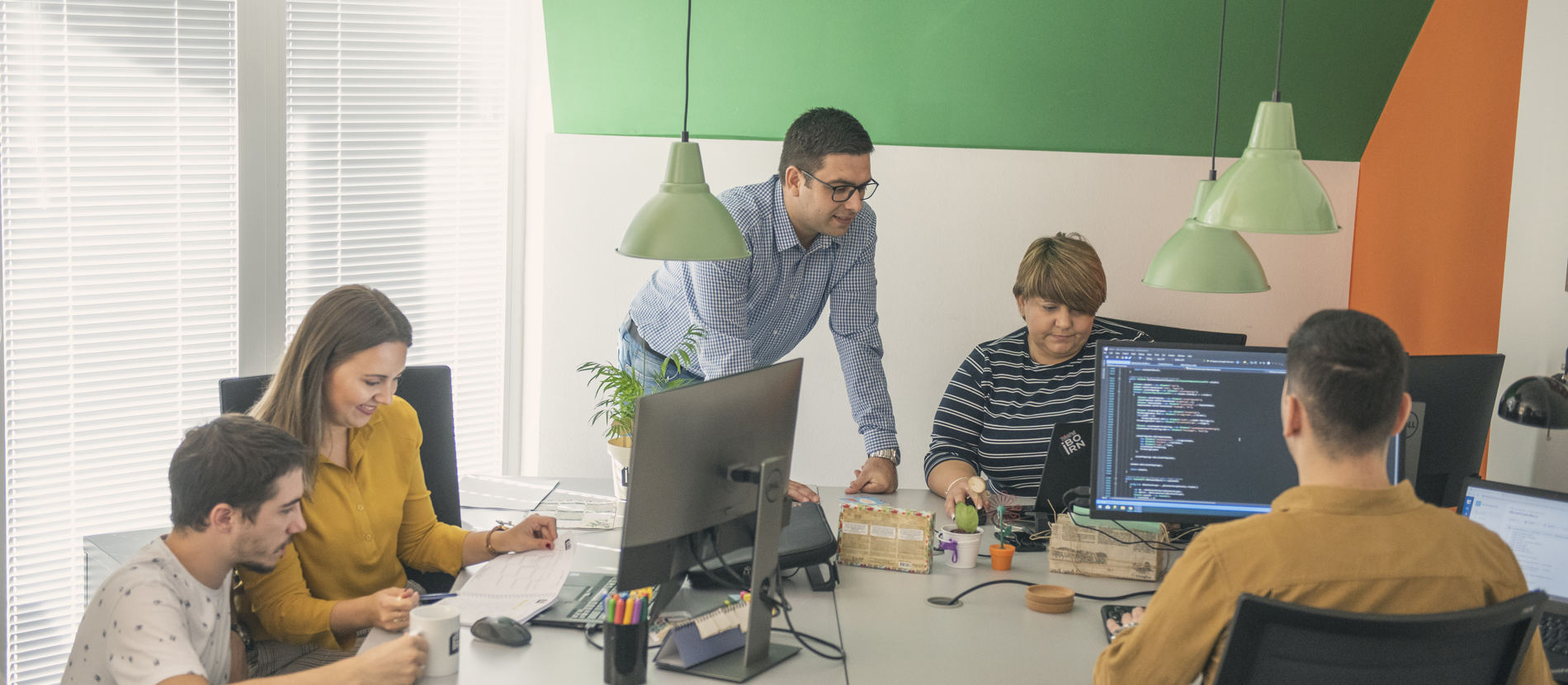 Employees focused on their work at computers in an office space.