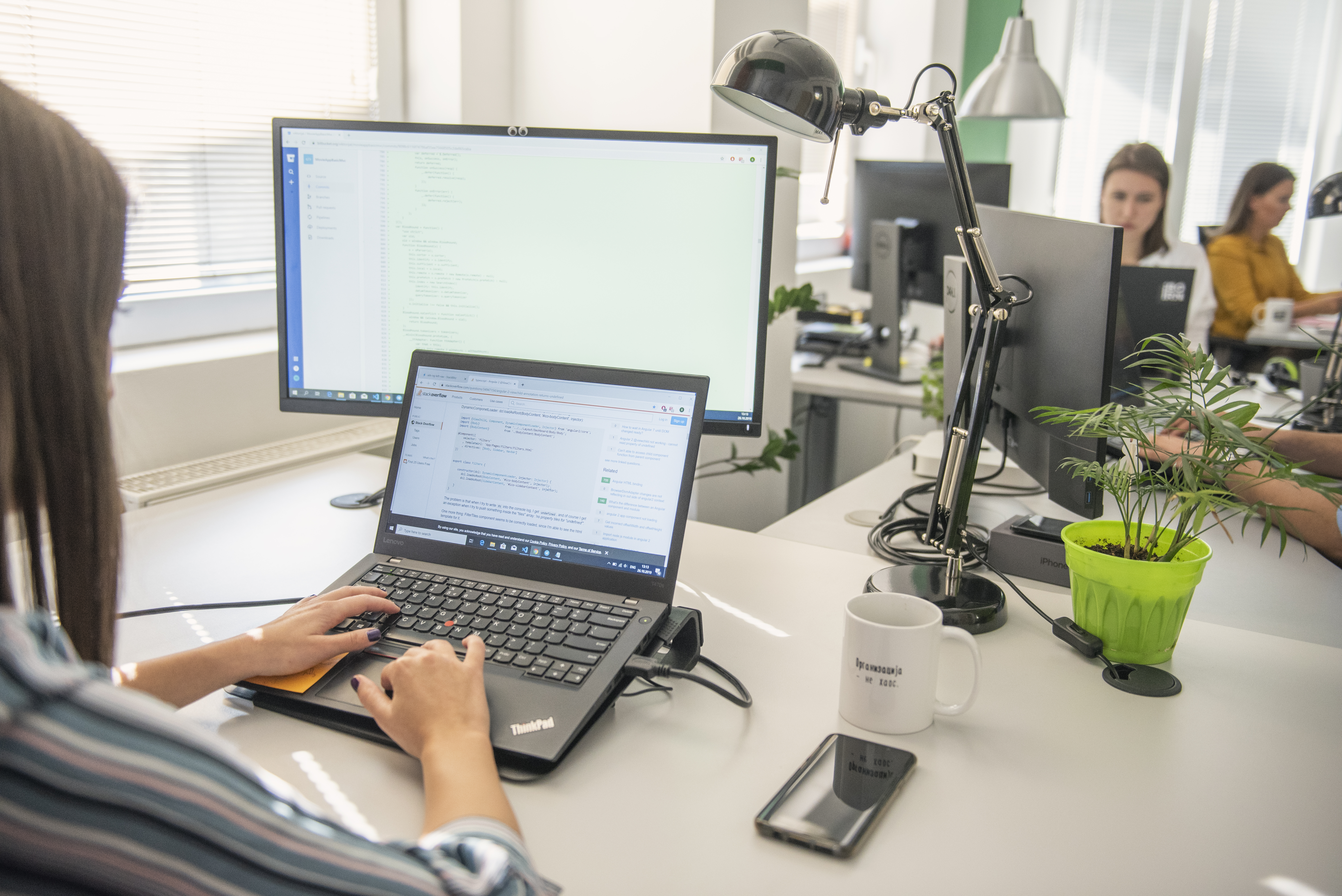 Software developers working on their laptops in a modern office environment.