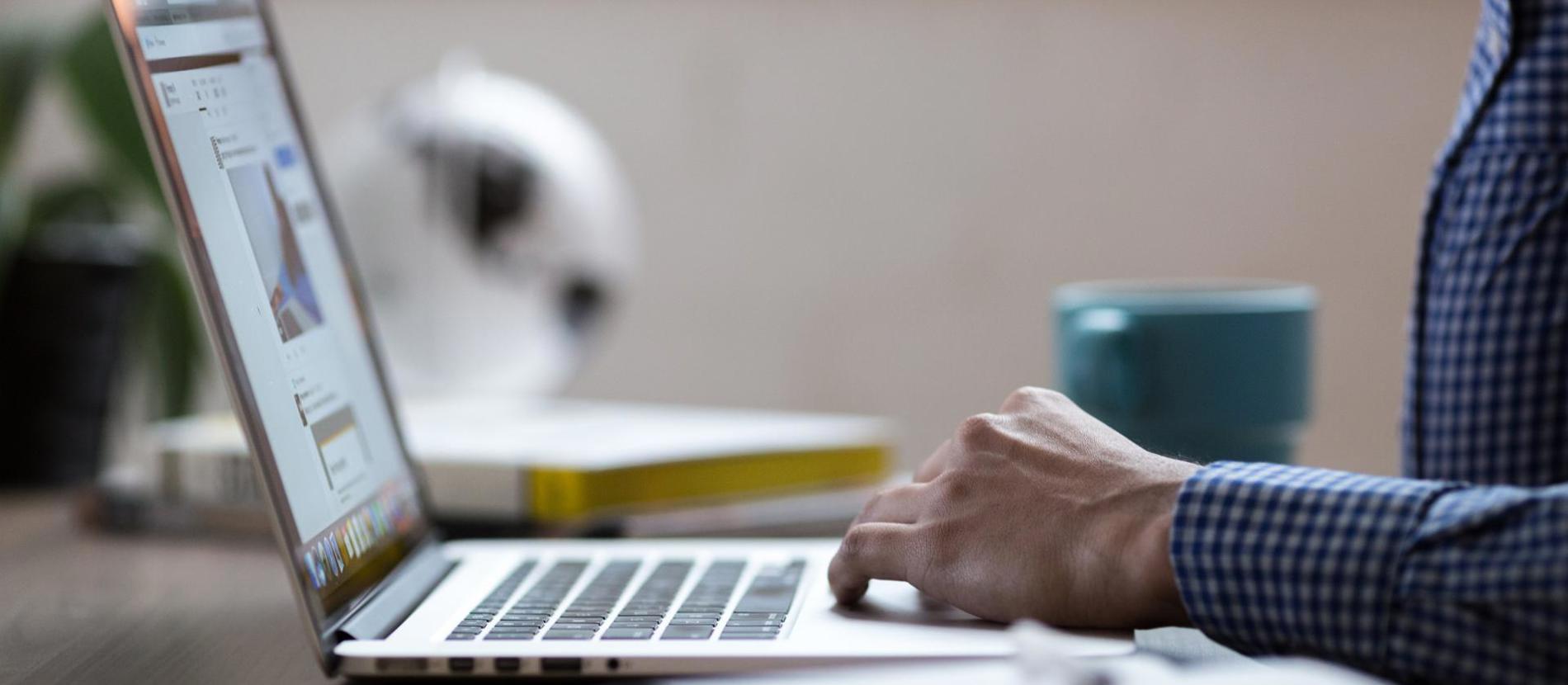 A woman sitting at a table with a laptop, focused on her work.