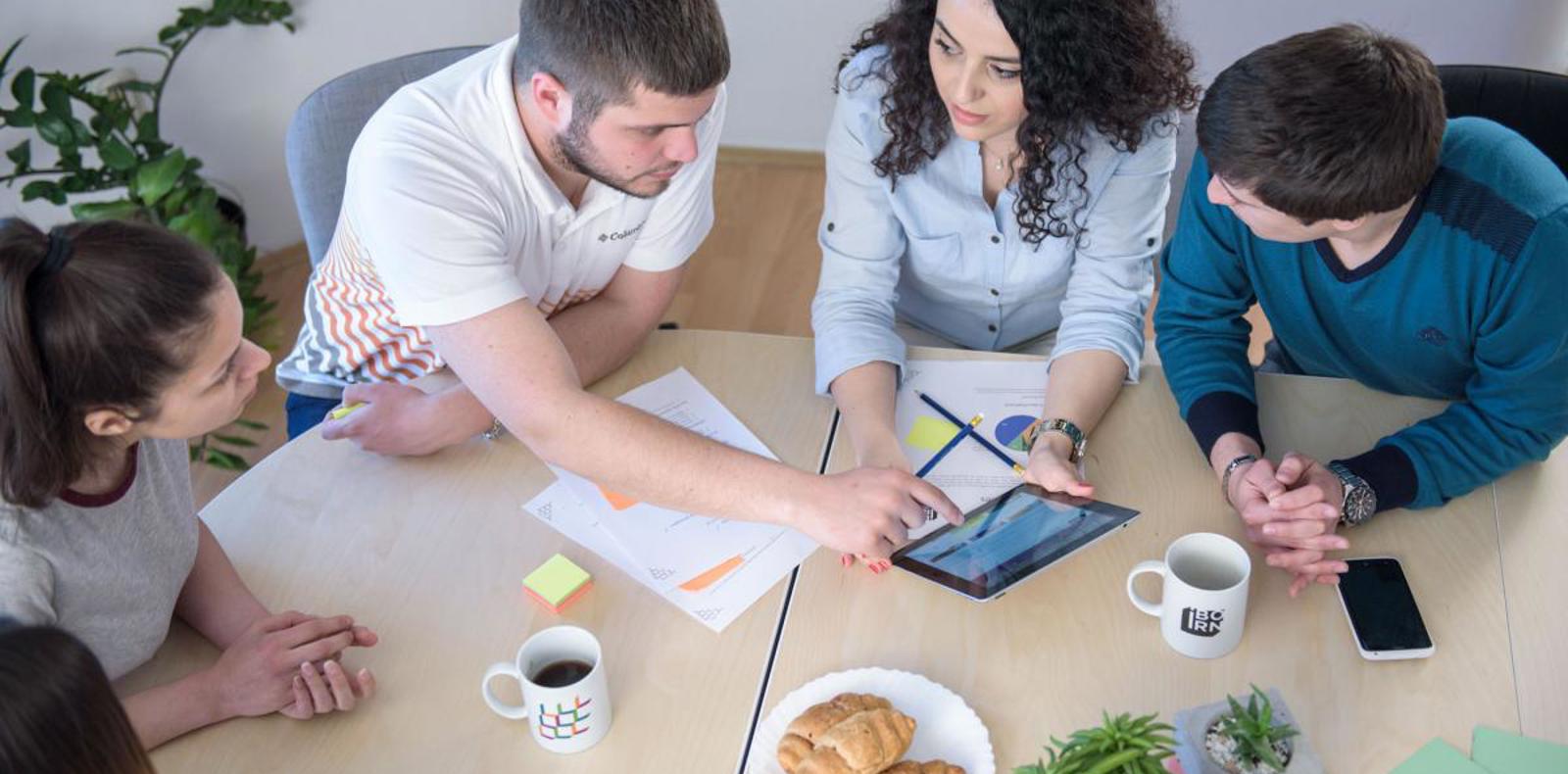 Group of colleagues having an informal meeting while drinking coffee and eating croissants. 