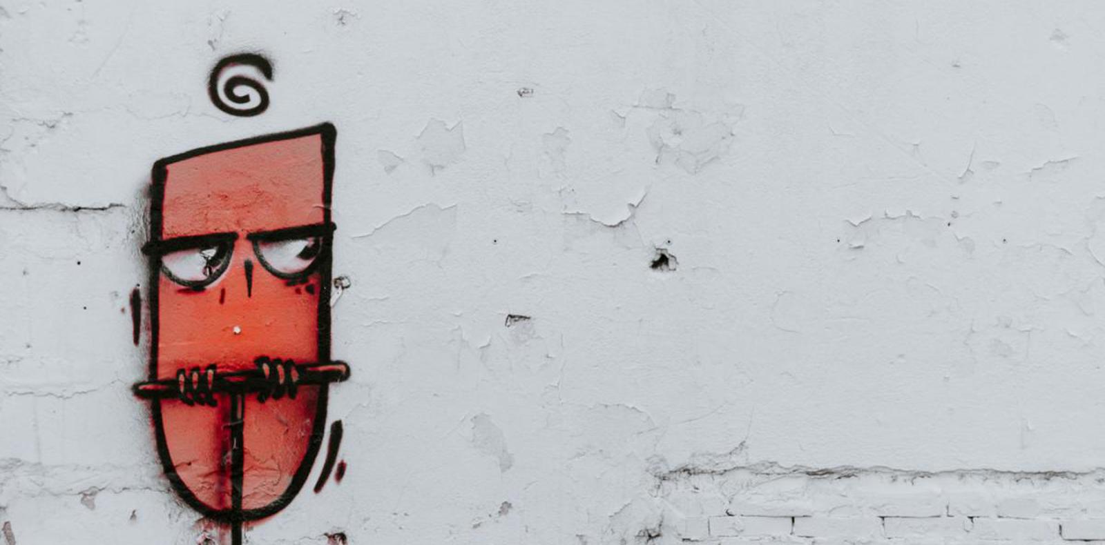 Red and black graffiti on white wall, urban street art style.