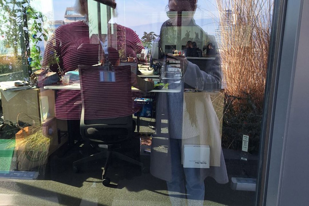 Two individuals wearing reindeer antlers seen in a mirror's reflection.