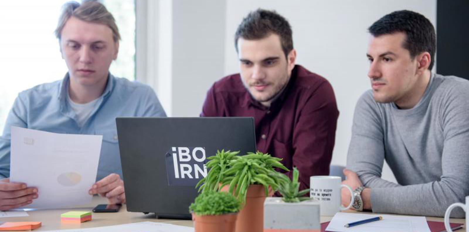 Data engineers collaborating at a table with a laptop in a meeting.