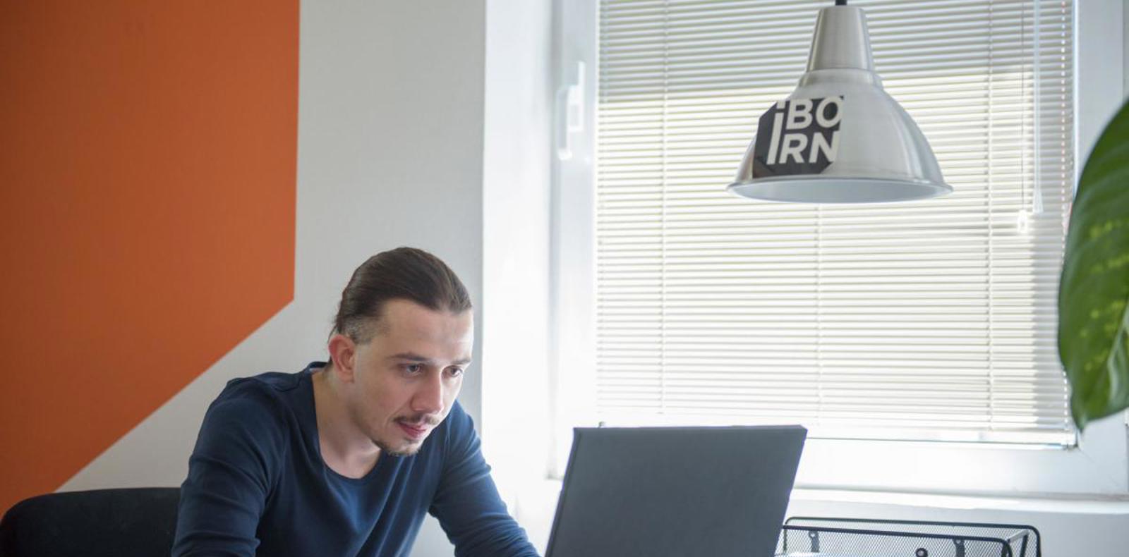 An individual seated at a desk, focused on using a laptop.