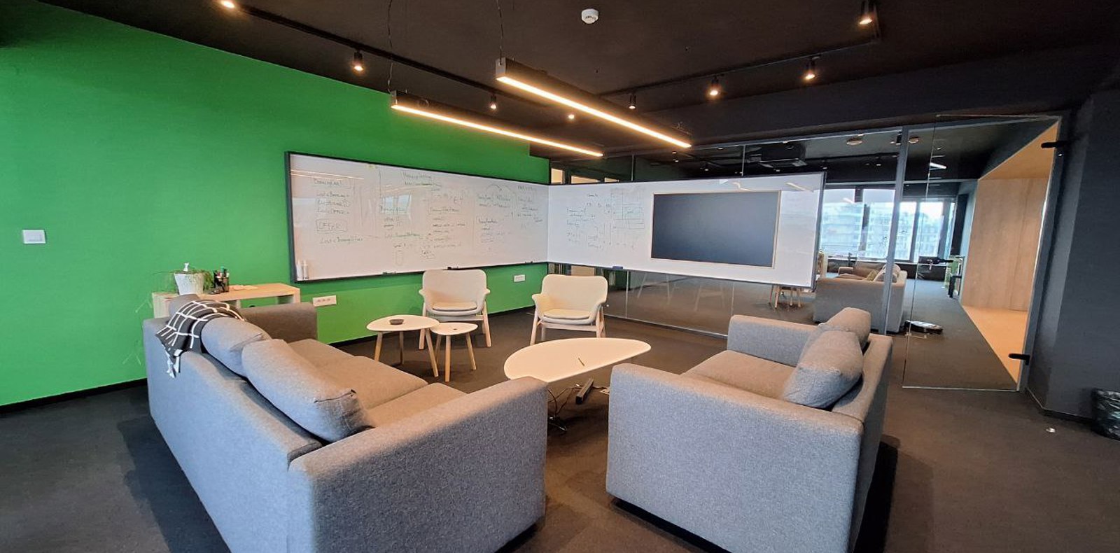 Modern and comfortable meeting room with sofas, chairs, big whiteboard, and smart TV.