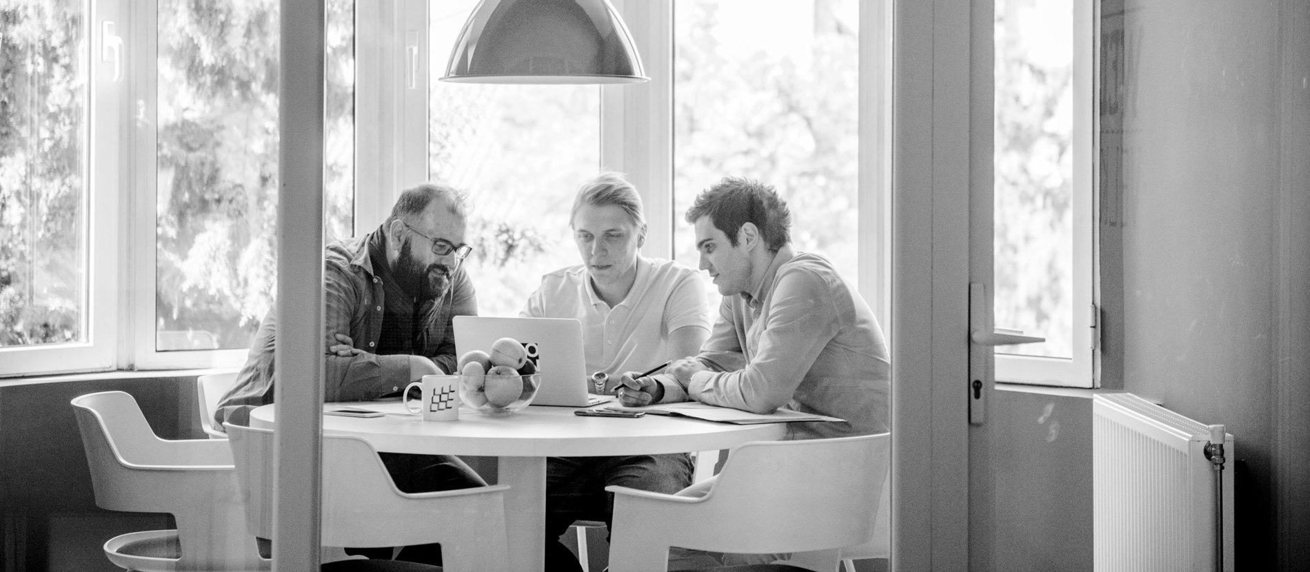 A group of individuals sitting around a table, engaged with a tablet device.