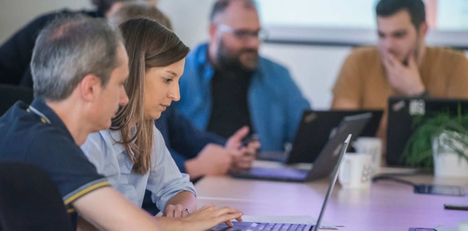 A  group of colleagues sitting at a table with laptops, working together on a project.