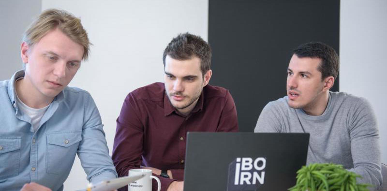 Three men working on their laptops at a table.