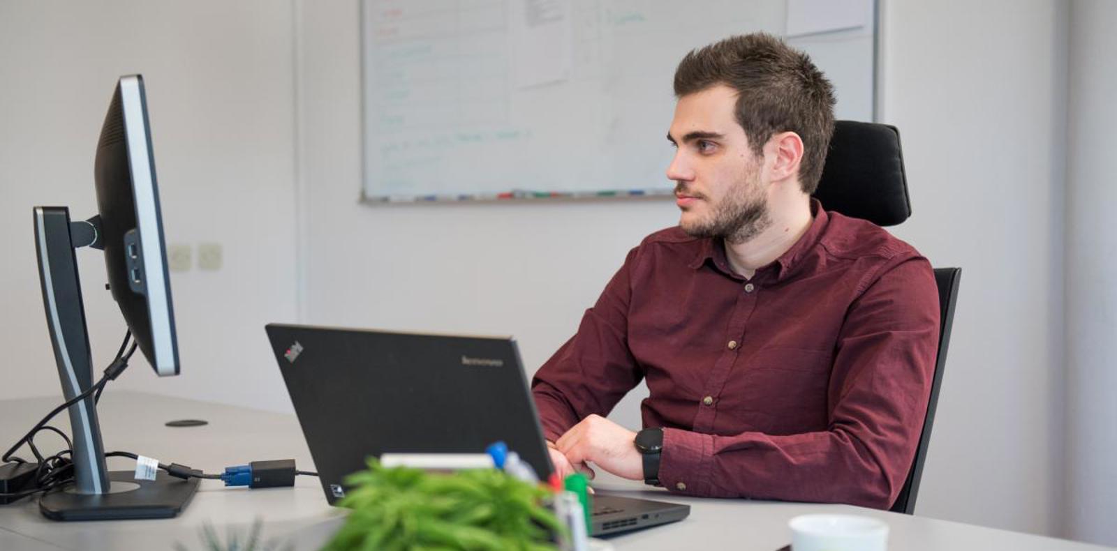 A man sitting at a desk with a laptop open in front of him.