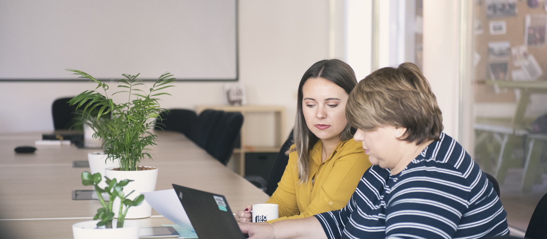 Two women discussing something on a computer screen.