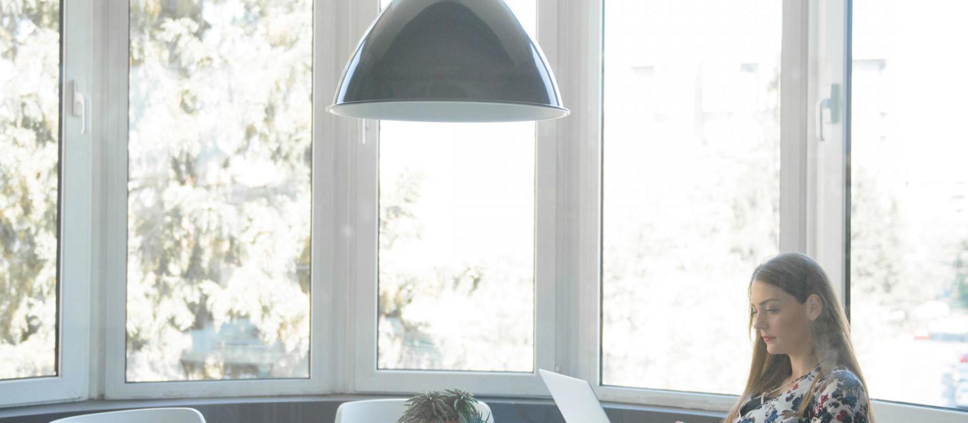 Laptop on a desk with a coffee mug, a small cactus, and a desk lamp.  