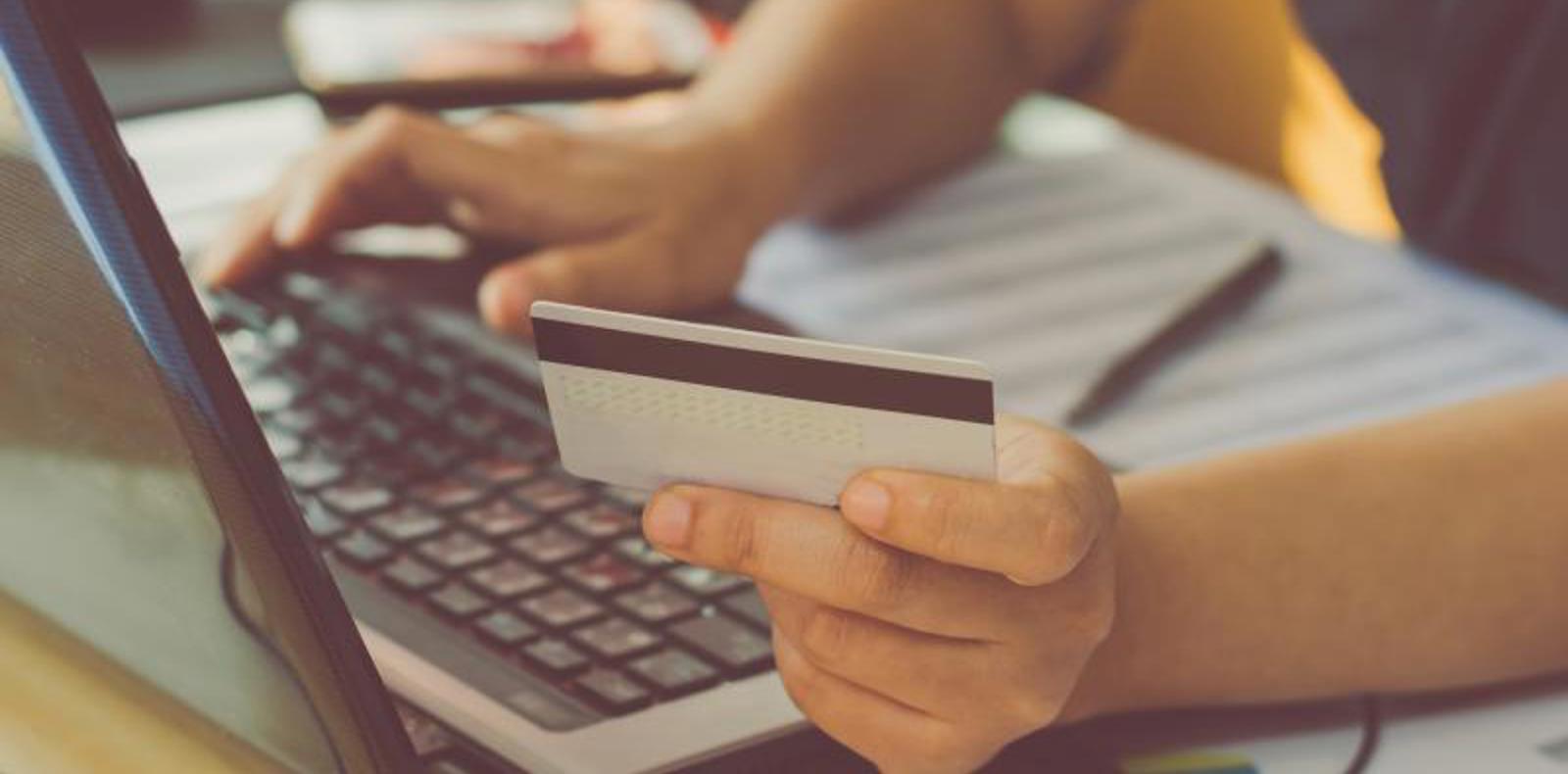 A person using a laptop to make a payment with a credit card.