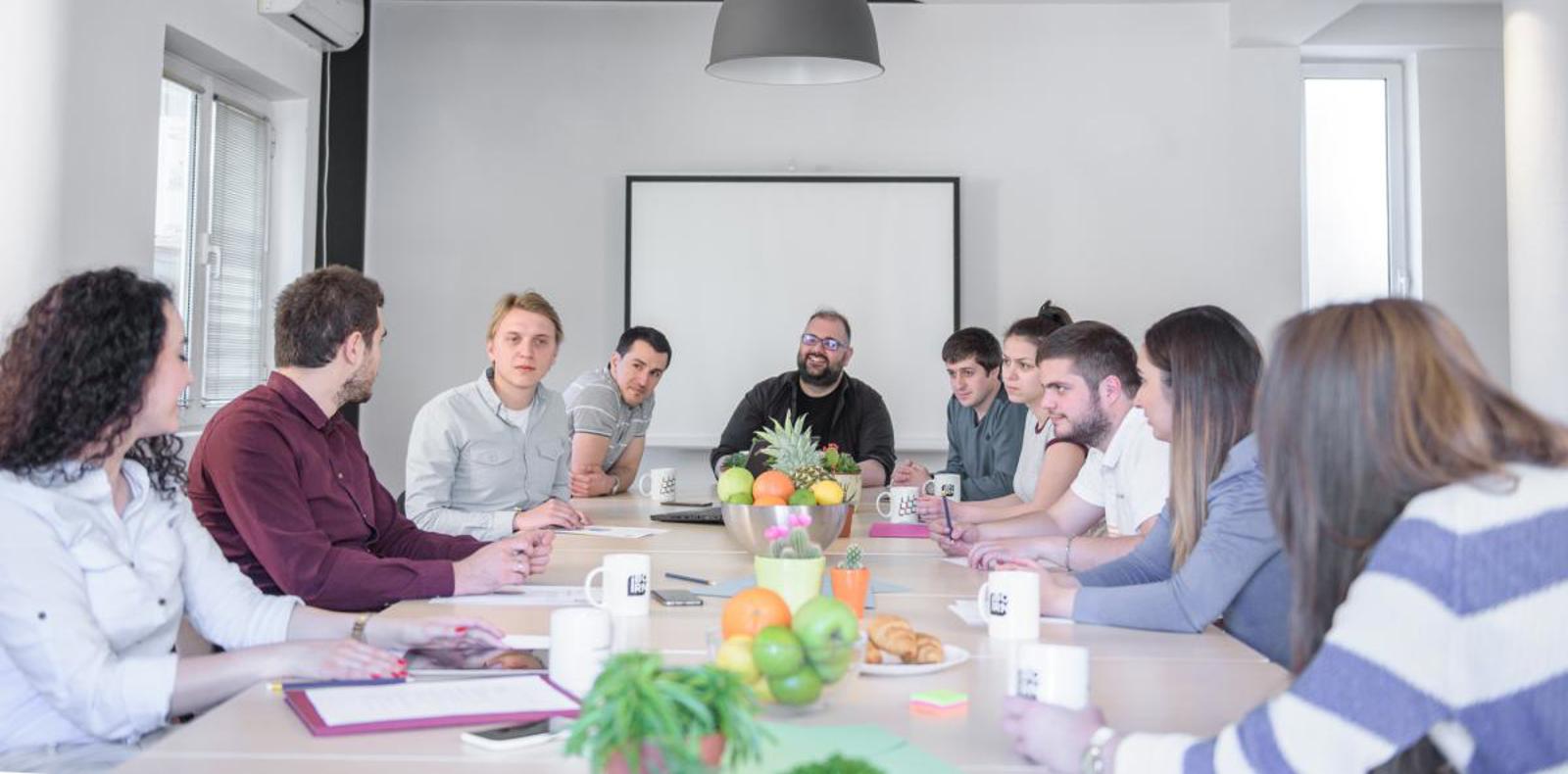 Software development team having a meeting and discussing work in a bright conference room. 