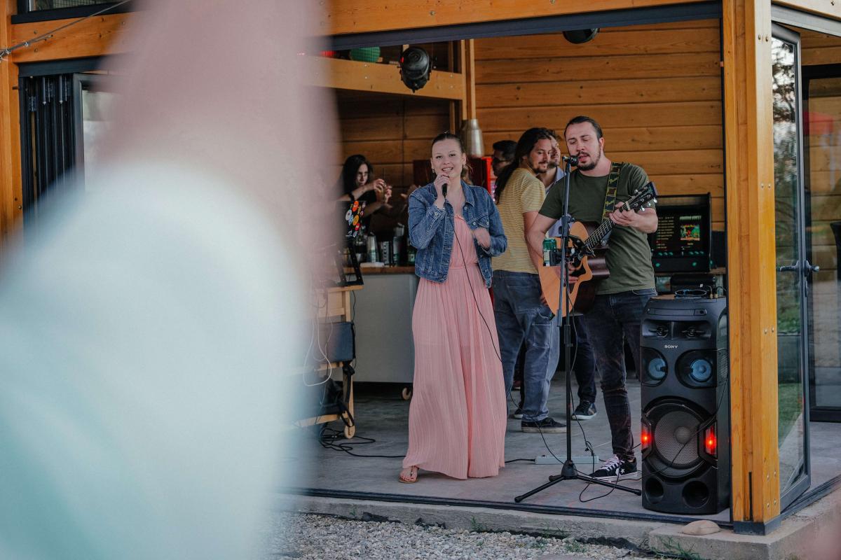 Woman singing and a man playing guitar during a founding anniversary picnic party