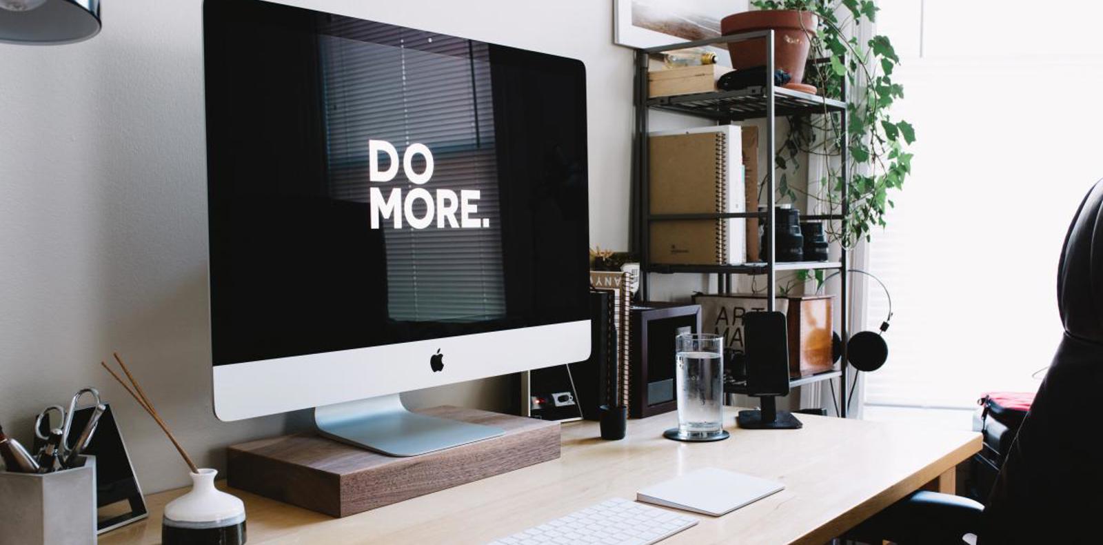 A desktop computer on a desk displaying a message Do More.