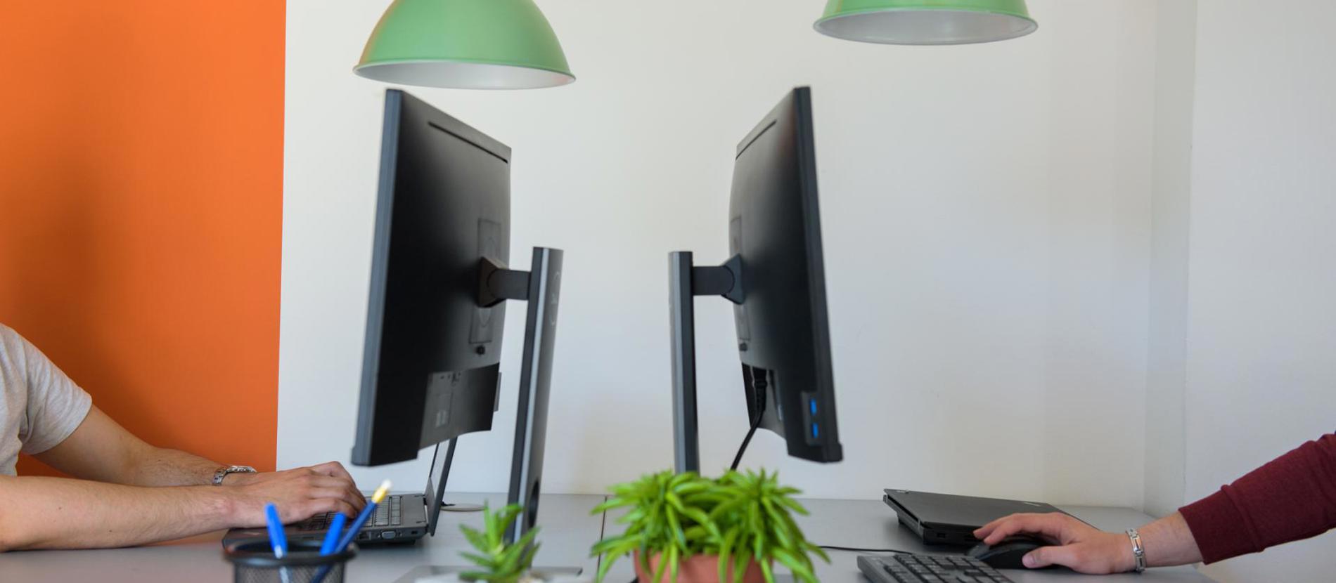 A modern computer desk with dual monitors and a keyboard, providing a productive workspace.