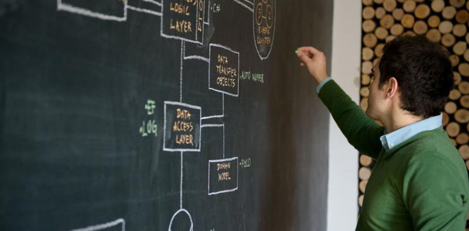 A man writing on a blackboard with diagrams.