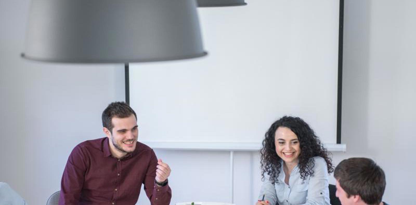 A team of colleagues discussing ideas and working together at a table in a professional office setting.