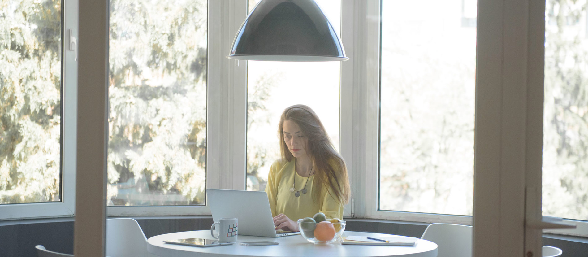 Close-up of computer and laptop screens with people working in the background.