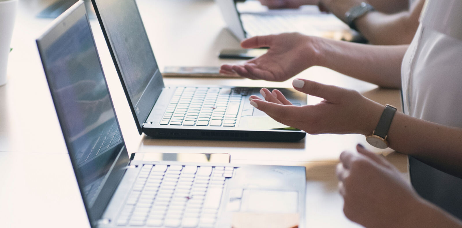 Several people sitting at a table with laptops, working together on a project.