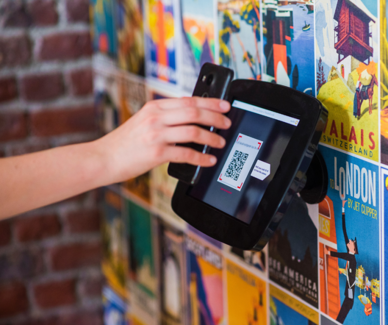 A person scans a QR code using a smartphone, utilizing the device's camera to capture the code for further processing or information retrieval.