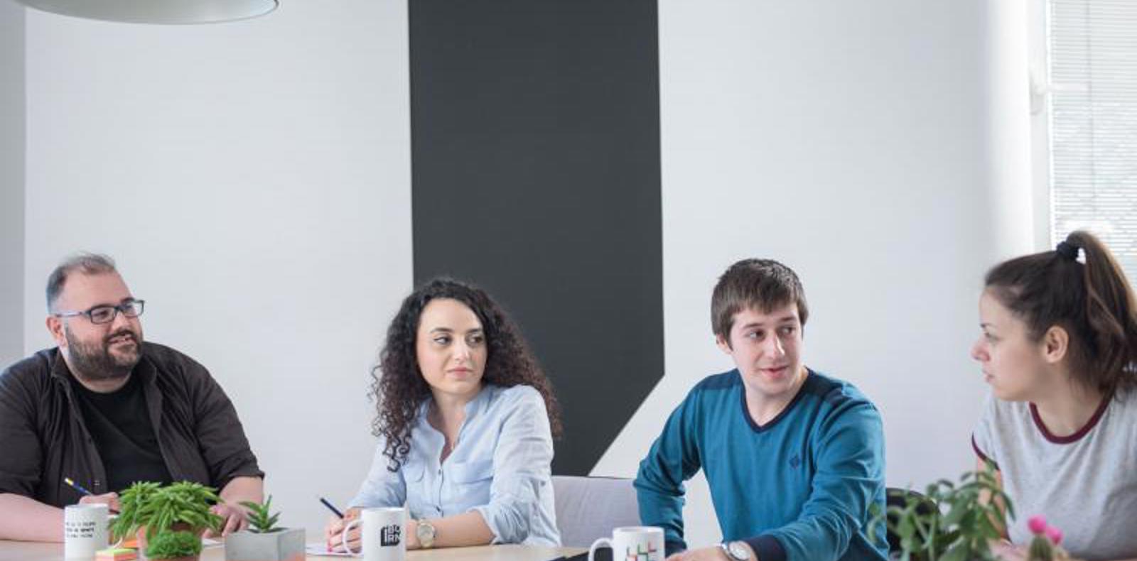 Office colleagues gathered around a table discussing work in a professional setting.