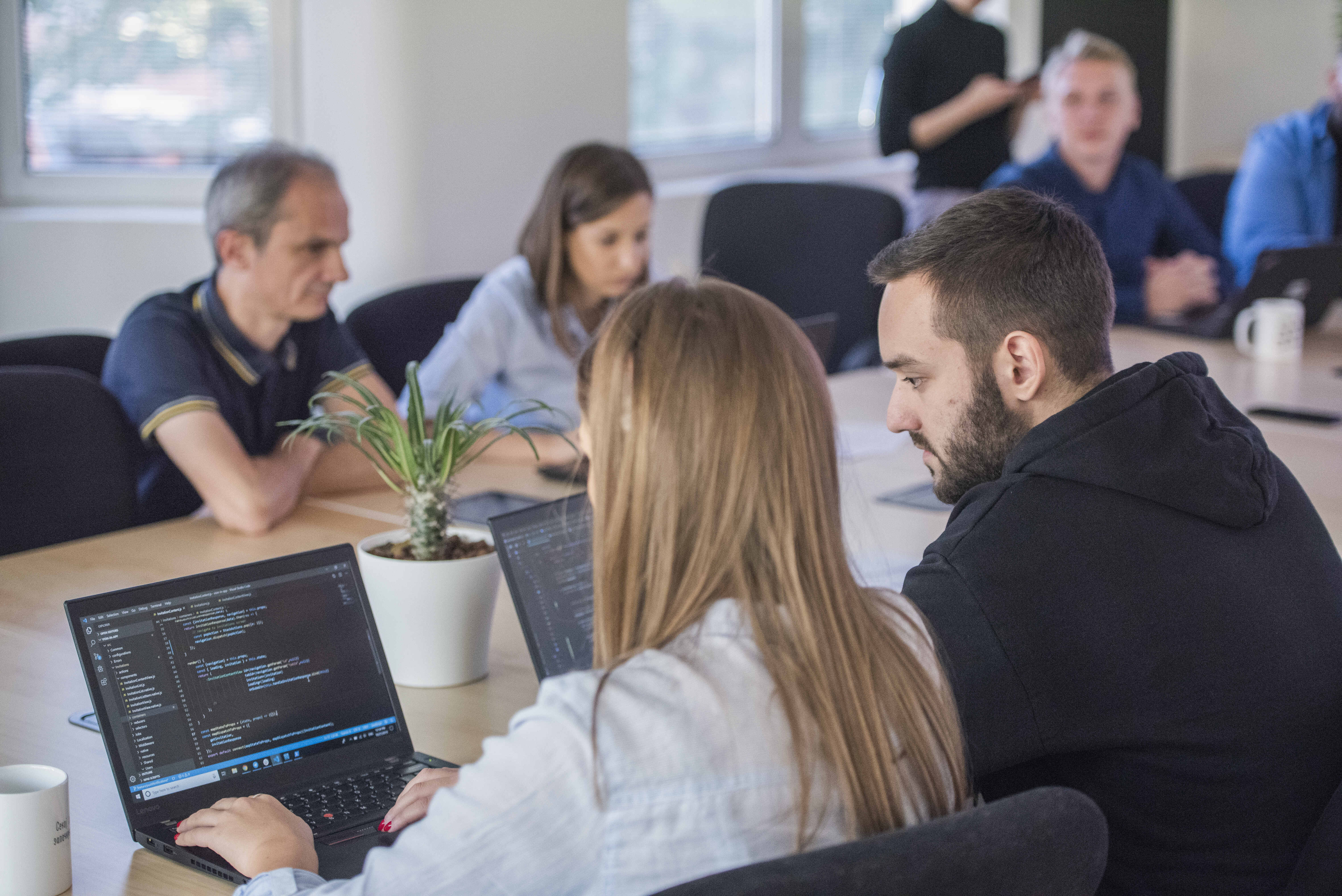 Software engineers working on a laptop in a conference room.