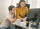 A man and woman sitting at a desk, engaged in conversation and working together on a project.