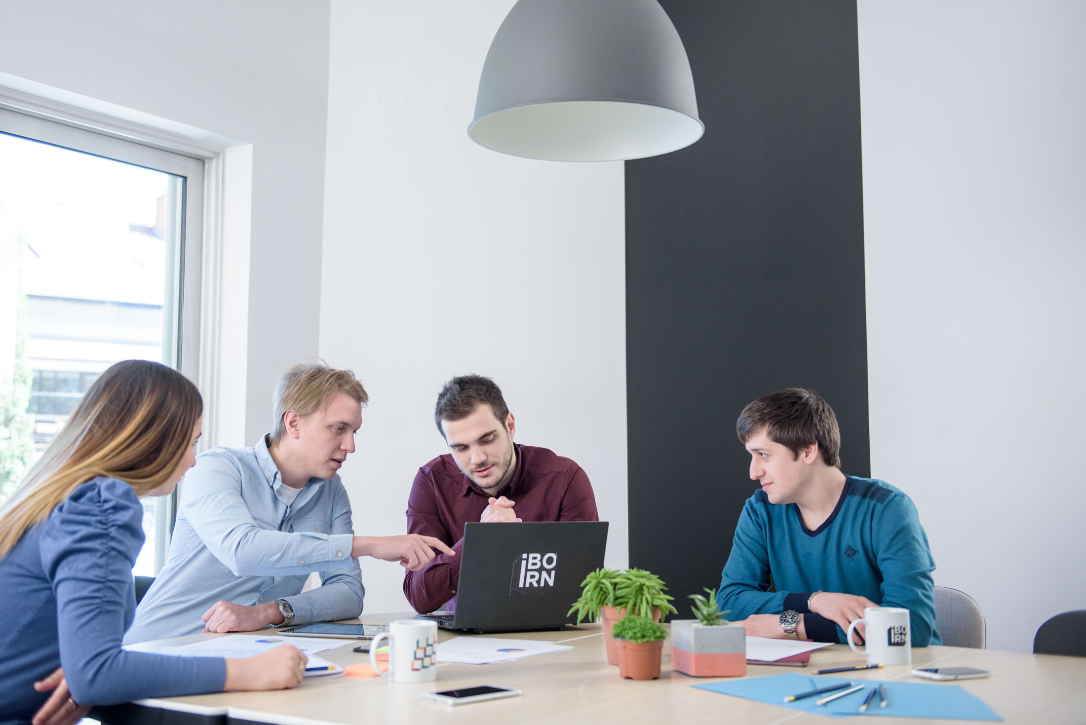 Three people collaborating at a table, focused on a laptop.