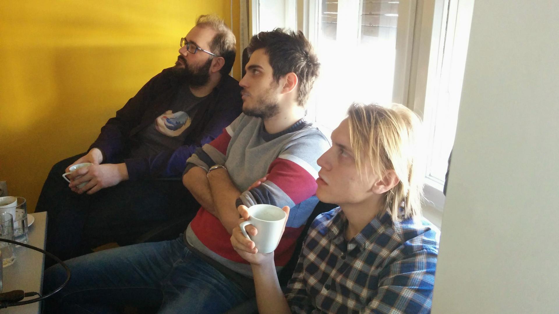 Three men listening to a presentation about React.Js Flux Architecture.