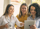 Three women standing in front of a window, engrossed in an iPad.