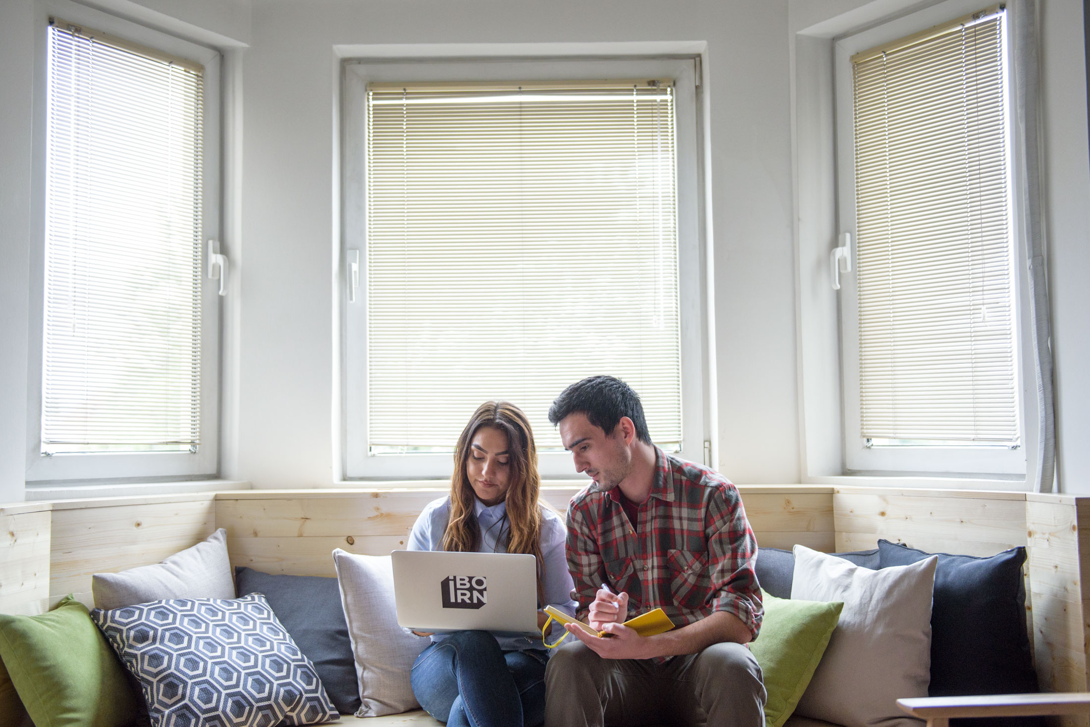 Man and woman using laptop on a couch.