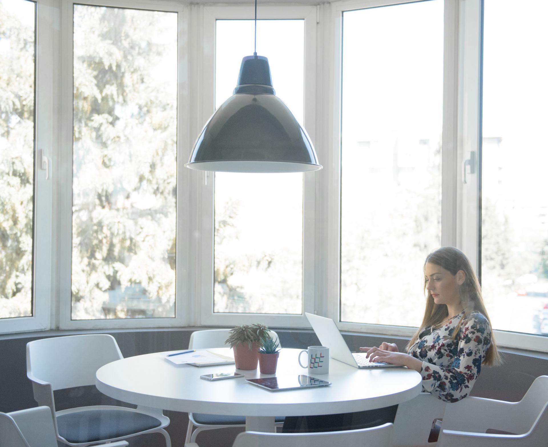 A woman sitting at a table with a laptop, focused on her work.