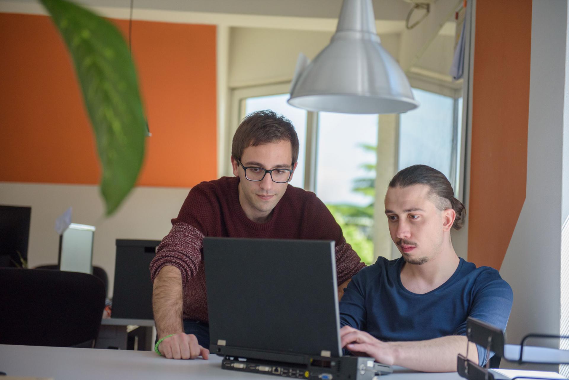 Two software engineers working together on a laptop.