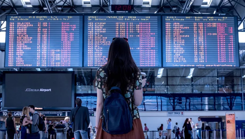 Woman checking flight schedule map outside airport terminal.