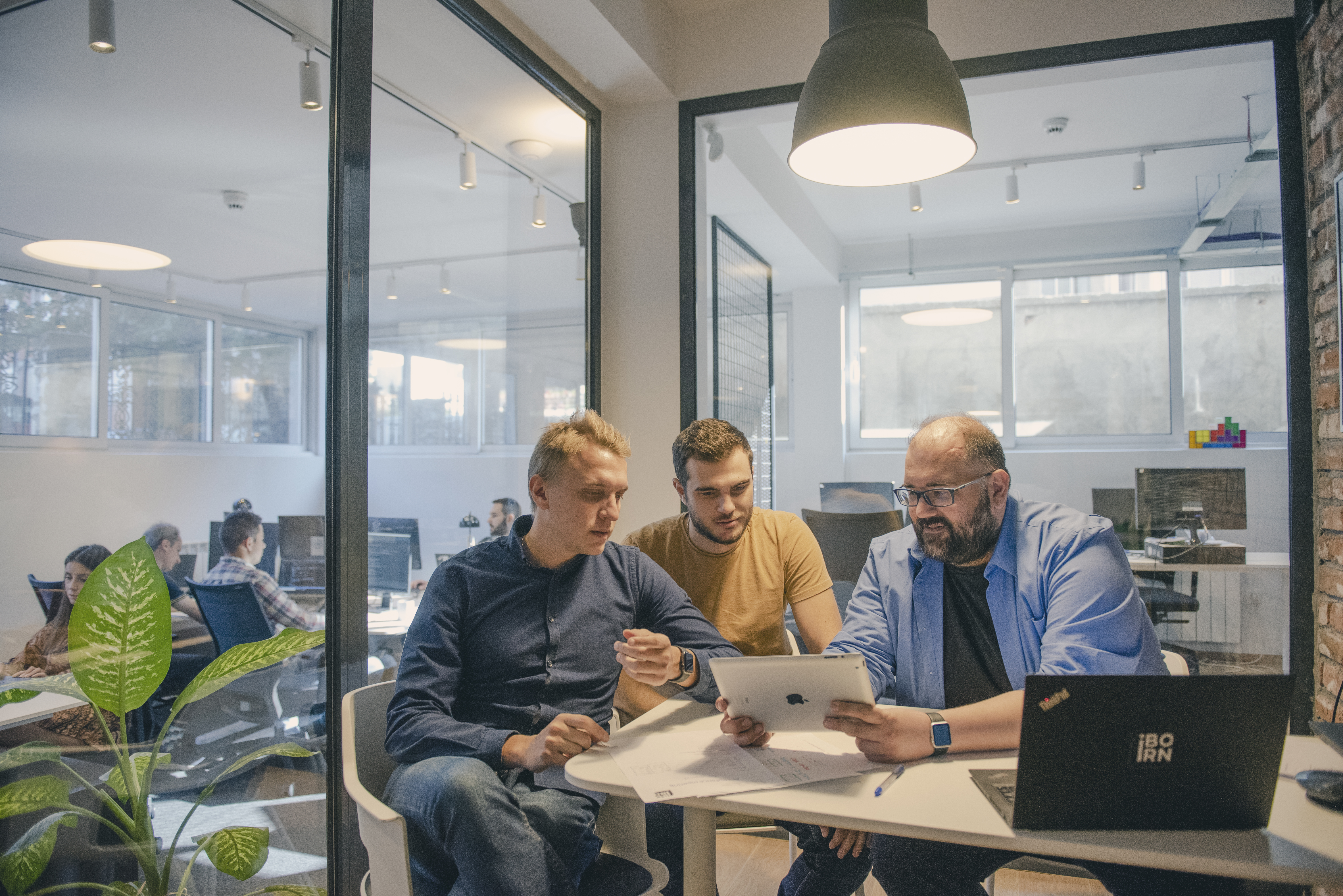 Three men focused on a laptop at a table.