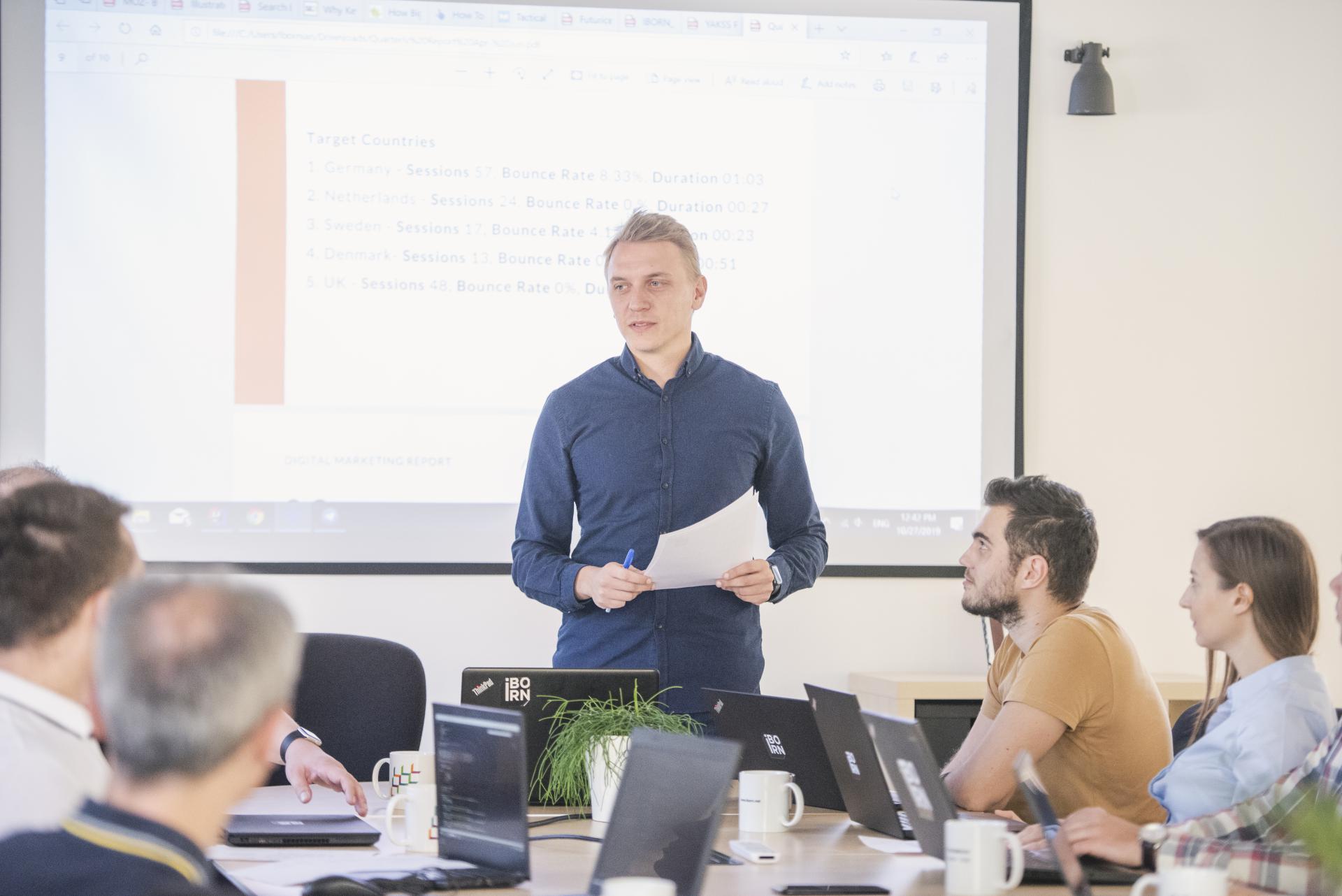 A man confidently presenting to a group of attentive individuals, engaging them with his informative and captivating presentation.