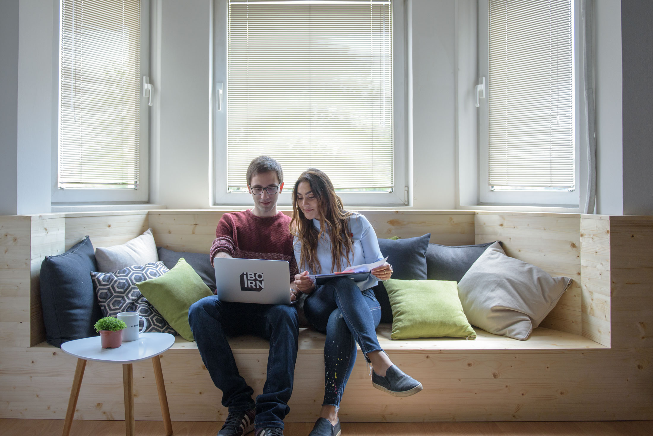 Man and woman using laptop on a couch.