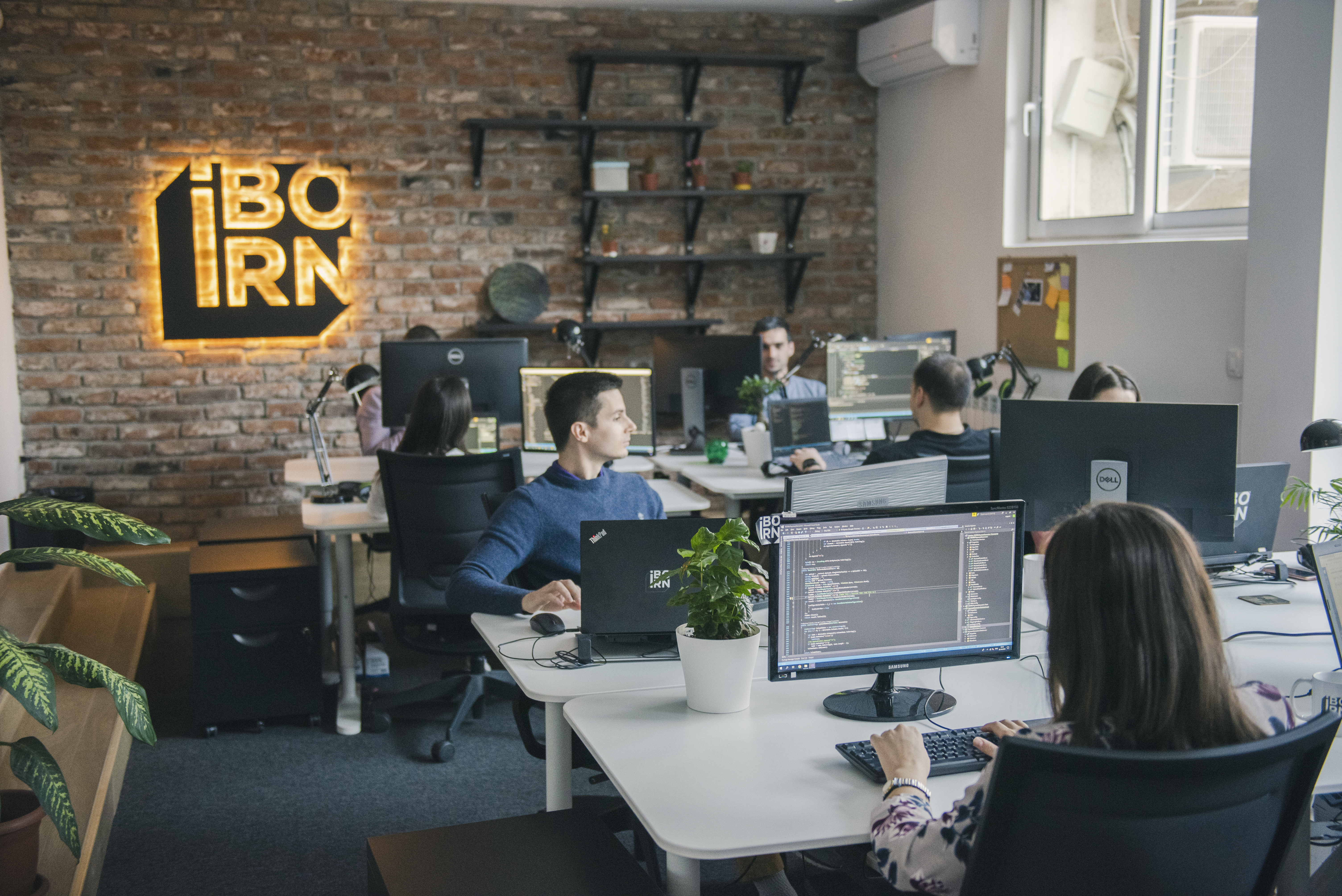 Employees working at desks in an office with computers.
